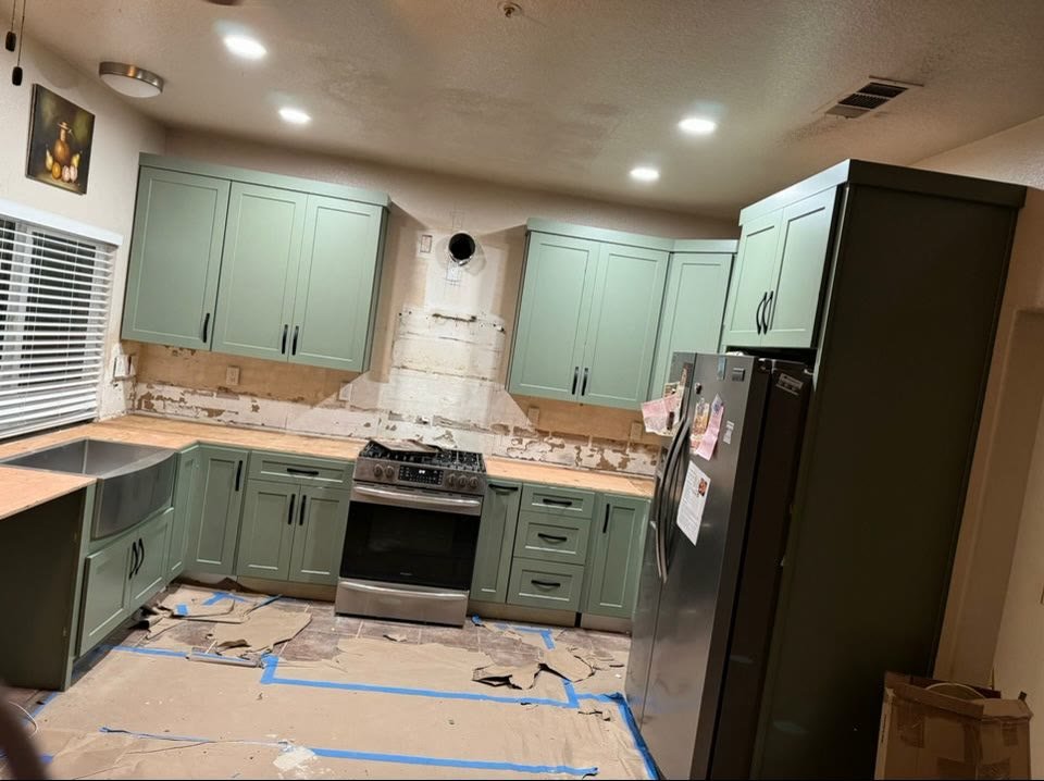 Sage green kitchen with new appliances during installation